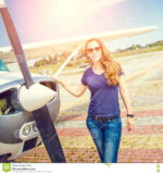 young-smiling-woman-standing-near-private-plane-ready-flight-warm-color-toned-image-aviation-school-background-81970246.jpg